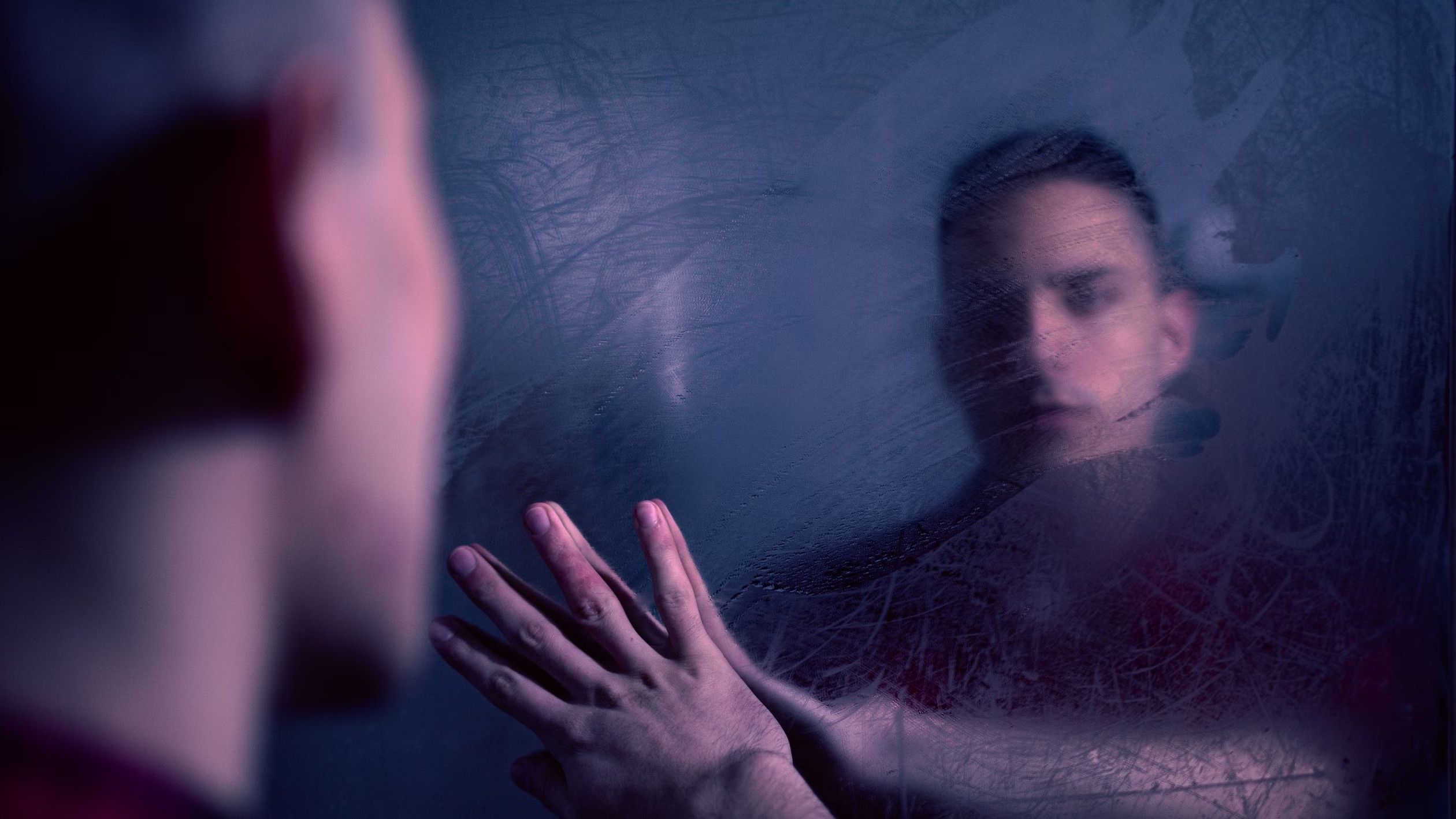 Homem observa o próprio reflexo desfocado em um espelho embaçado.