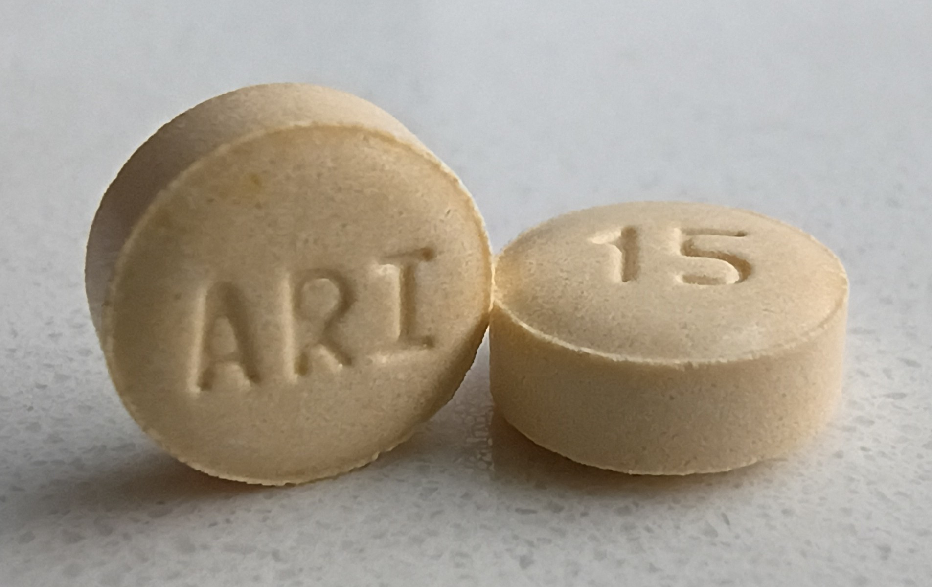 Dois comprimidos de aripiprazol sobre uma superfície cinza.