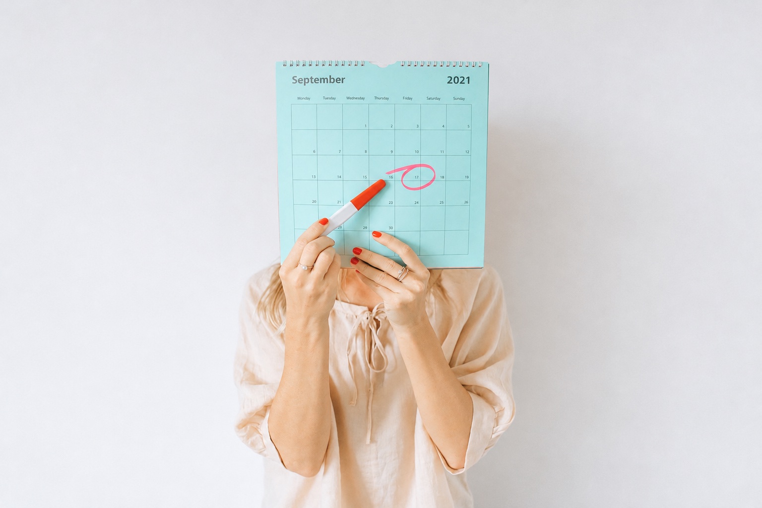Mulher segura um calendário com uma data circulada e um teste de gravidez.