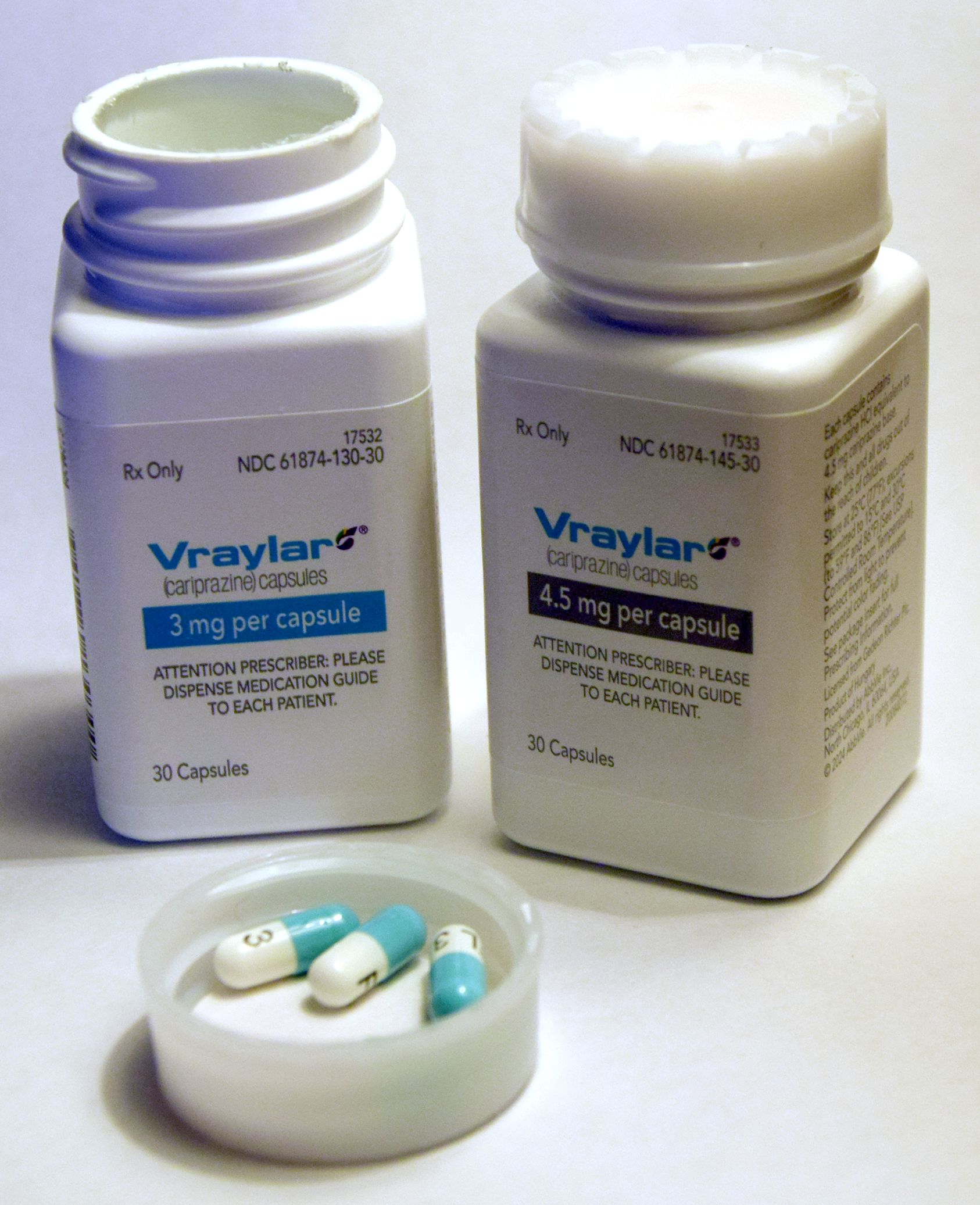 Dois frascos de Vraylar, com cariprazine escrito no rótulo, e cápsulas sobre uma tampa.