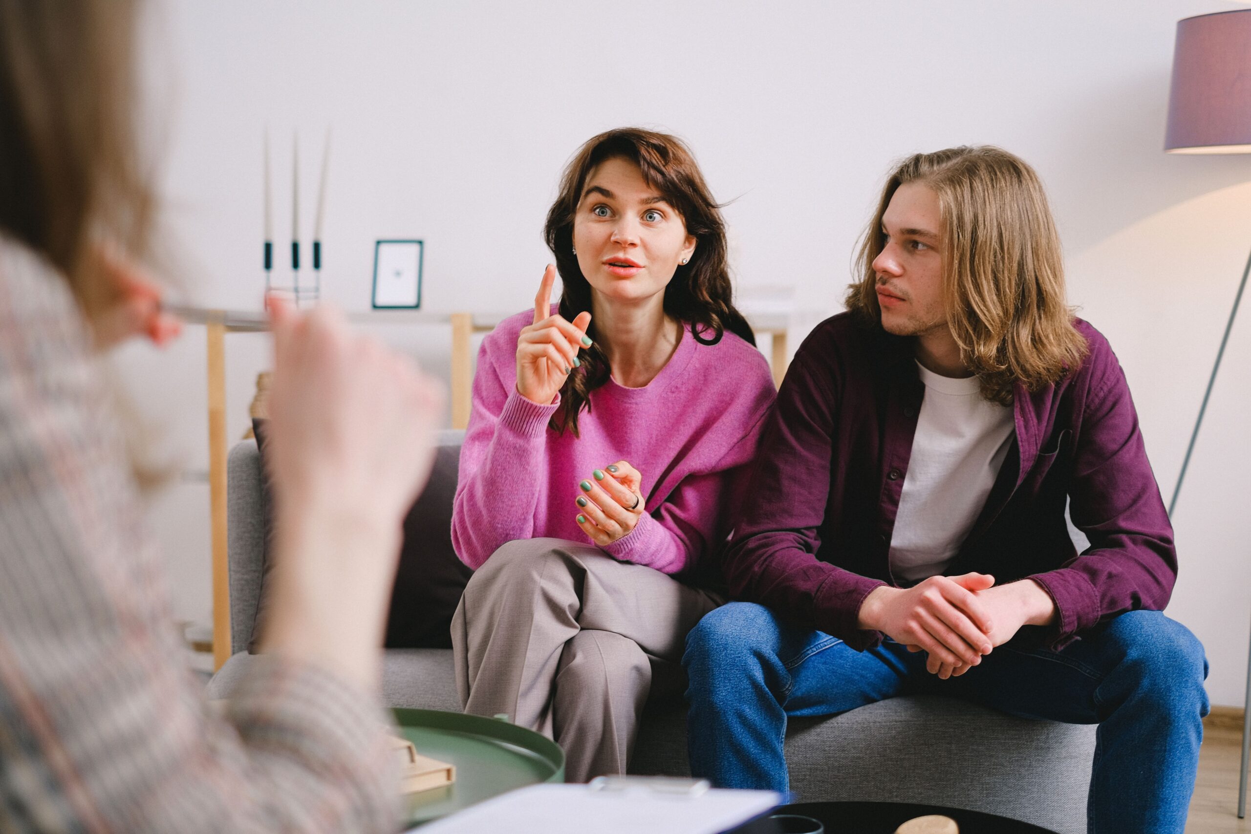 Mulher conversa com terapeuta enquanto o companheiro acompanha a sessão ao seu lado.
