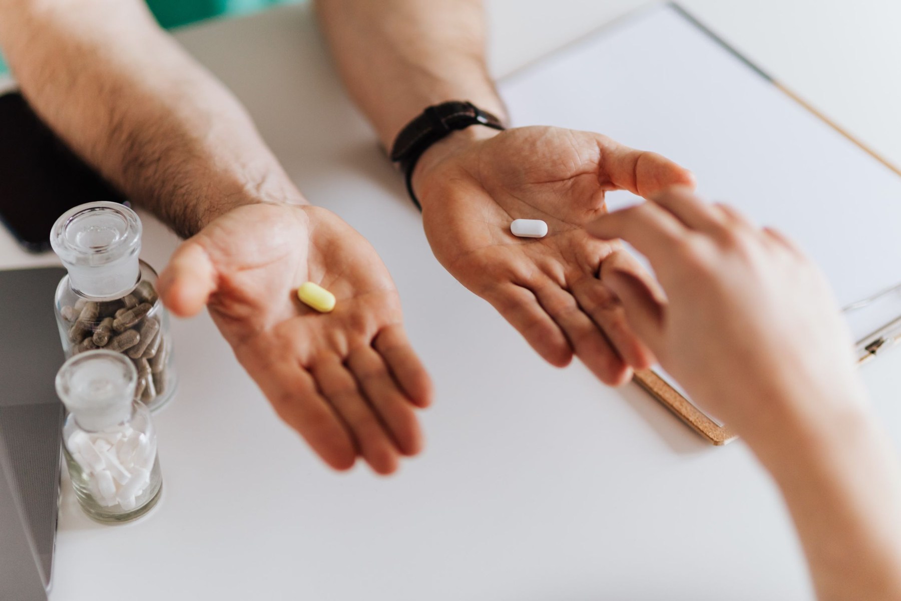 Mãos apresentam dois comprimidos diferentes durante uma consulta.