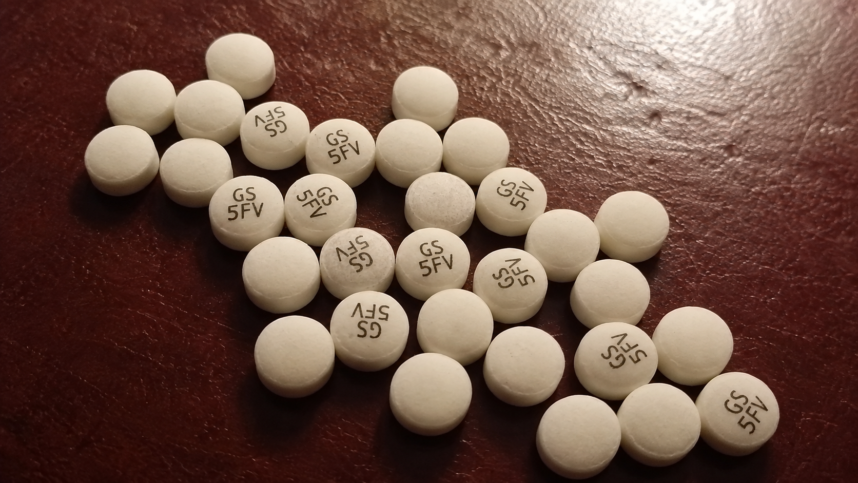 Comprimidos brancos de bupropiona XL sobre uma superfície marrom.